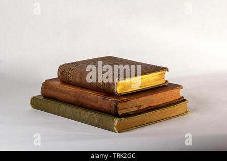 Pila di tre libri antichi su uno sfondo bianco. Foto Stock