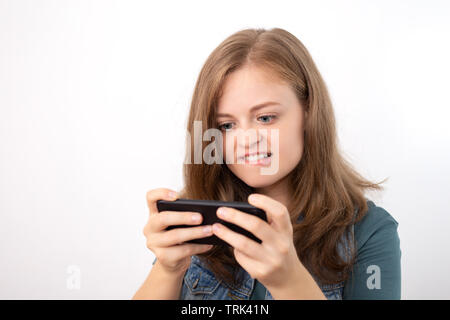 Giovane donna caucasica texting o la riproduzione di gioco sul telefono cellulare Foto Stock