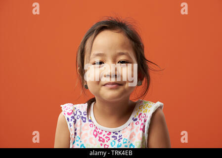 Close-up ritratto luminoso della ragazza asiatica isolato sul colore arancione Foto Stock