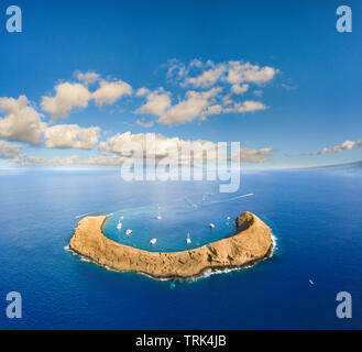 Molokini cratere, antenna colpo di forma di una mezzaluna isolotto a metà mattina con barche a noleggio, Maui, Hawaii. Foto Stock