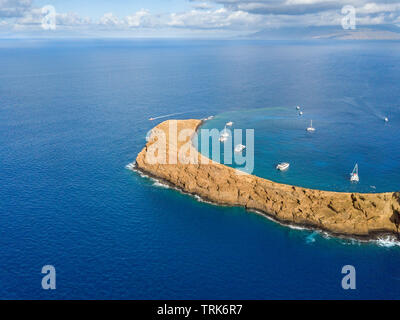 Molokini cratere, antenna shot guardando la parete posteriore della forma di una mezzaluna isolotto a metà mattina con barche a noleggio interno, Maui, Hawaii. Foto Stock