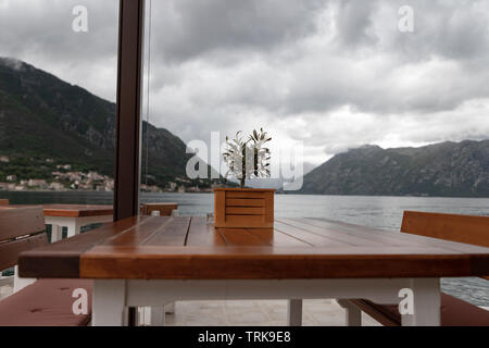 Dobrota, Montenegro - tavolo e sedie a sdraio sulla terrazza sul mare dopo la pioggia a molla Foto Stock