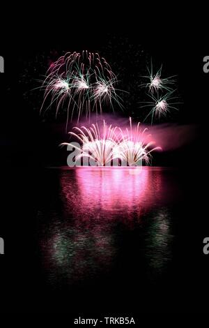 Bellissimi fuochi d'artificio colorato sulla superficie dell'acqua. Scena notturna. Concetto per feste e celebrazioni. Foto Stock