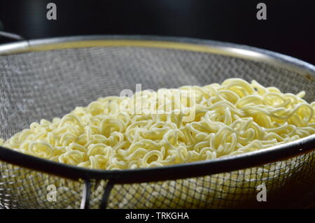 Bollito di noodle istantanei su inossidabile scolapasta Foto Stock