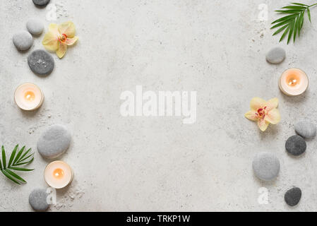 Spa concept sulla pietra bianca di sfondo, foglie di palmo, fiori, candele e zen come pietre grigie, vista dall'alto, copia dello spazio. Foto Stock
