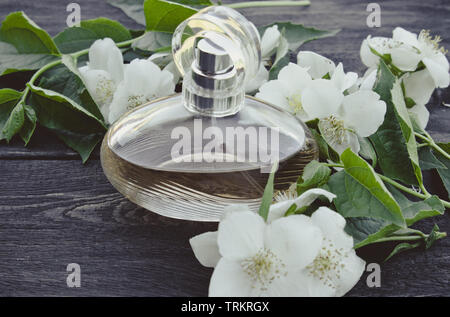 Bottiglia di profumo con fiori di gelsomino su sfondo di legno. Le donne del profumo con il profumo di gelsomino. Foto Stock