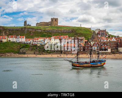 Nave a vela nel porto di Whitby con Abbazia in background A. Popolare meta costiera per turisti e turisti a nord Costa dello Yorkshire Foto Stock