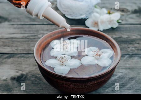 Gelsomino olio essenziale e fiori sul tavolo di legno dello sfondo. Procedure cosmetiche Foto Stock