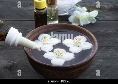 Essenziale olio aromatico al gelsomino su sfondo di legno. Messa a fuoco selettiva. Foto Stock