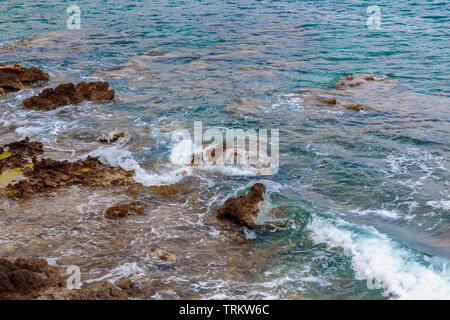 Vista dell'oceano al bellissimo Canyamel su Mallorca, Spagna, con onde che si infrangono sulla spiaggia rocciosa. Foto Stock