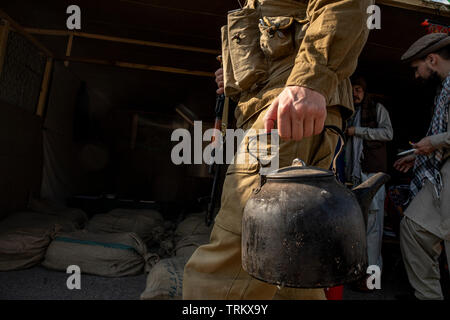 Esercito sovietico soldato va con un bollitore sul villaggio afghano durante la guerra in Afghanistan (1979-1989). Ricostruzione storica della vita dell'esercito sovietico Foto Stock