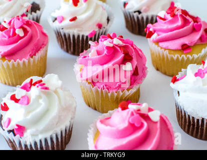 Tortini di San Valentino con il colore rosa e bianco di glassa di colore e di cuore spruzza sulla parte superiore Foto Stock