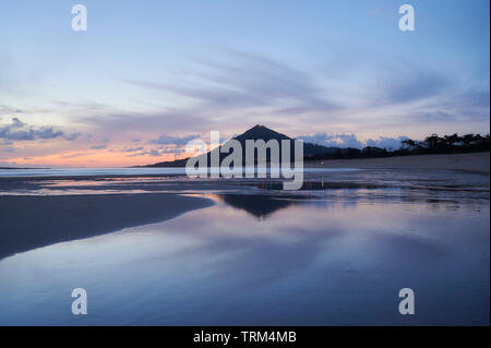 Spiaggia di moledo alla fine della giornata, con vista montagna trega sul lato spagnolo del confine. La bassa marea visualizzando la spiaggia sabbiosa su una torbida da Foto Stock