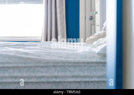 Basso angolo di visione di un dormito nel letto con un confuso foglio, non coperte, in azzurro e bianco camera da letto home design. Foto Stock