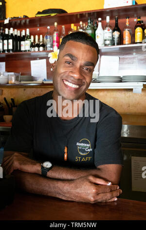 Ritratto di un sorridente Melanesian barman indossando un fiore di frangipani dietro il suo orecchio, Port Vila, l'isola di Efate, Vanuatu, Melanesia Foto Stock