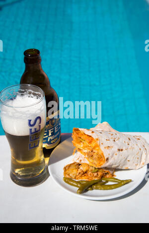 Un piatto di pollo turco kebab (Tavuk frumento} serviti con una bottiglia fredda di Efes birra Pilsen su un bel pomeriggio di sole in piscina, Marmaris, Turchia Foto Stock