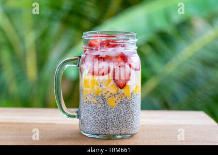 Latte di Mandorla chia pudding con fragole fresche e mango in un vasetto di vetro mug. Vegan materie prima colazione. Semi di Chia e taglio freschi frutti e bacche desser Foto Stock