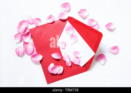 Busta rossa con una nota vuota e petali di rosa Foto Stock