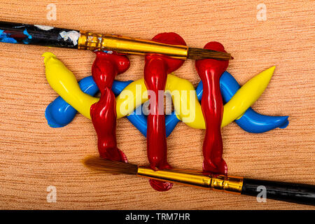 Acrilico Dell'artista dipinge in colori primari rosso, giallo e blu, in uno schema simmetrico con spazzole su una tavolozza di legno pronto per essere miscelati insieme o Foto Stock