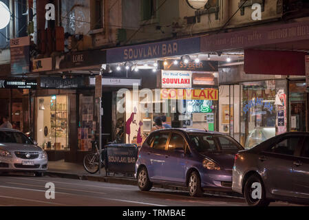 Tempo di notte al di fuori di una fila di negozi tra cui un greco souvlaki bar su Brunswick Street, Fitzroy, Victoria, Australia Foto Stock