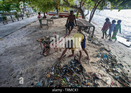 Isola di Papua gli abitanti di un villaggio di clearing fino in plastica rifiuti marino oggetto di dumping sulla loro spiaggia durante una giornata di vento nel Manyaifun sull isola di Batang Pele, West Foto Stock