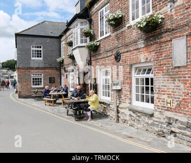 Padstow, Cornwall, England Regno Unito: gente seduta ai tavoli godendo bevande al di fuori dei maestri d'ascia Inn dal porto. Foto Stock