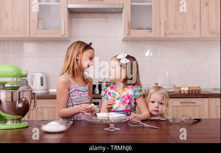 La grande famiglia - una madre e tre bambini - due figlie ed un figlio, cuoco in cucina, montare la panna in un frullatore. Messa a fuoco selettiva. Foto Stock