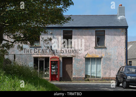 Esterno del fatiscente Magazzini Generali negozio del villaggio in Mathry, Pembrokeshire, Regno Unito con un rosso in disuso casella telefono, ora una libreria comunitaria Foto Stock