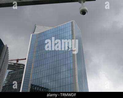 Occhio al cielo: una videocamera di sicurezza sembra come se è alta al di sopra di un grattacielo di Londra mentre un aereo passato è riflessa nel vetro Foto Stock