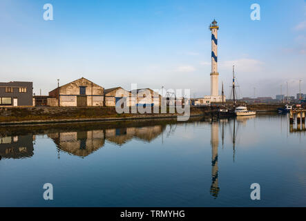 Il famoso faro di Ostenda in città con un riflesso in una delle banchine commerciali del porto, Fiandre Occidentali, Belgio. Foto Stock