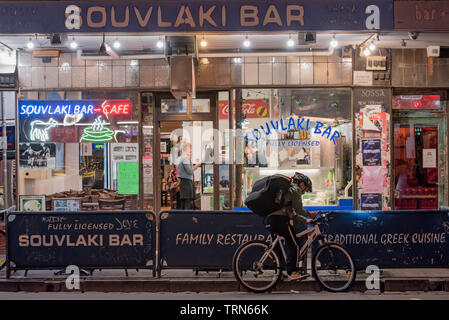 Una consegna del cibo ciclista di notte al di fuori di un greco souvlaki bar su Brunswick Street, Fitzroy, Victoria, Australia di notte Foto Stock