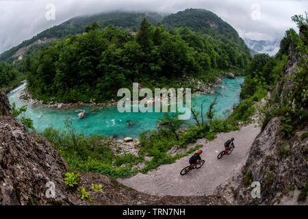 Due uomini ride mountain bike su un sentiero accanto alle acque turchesi del fiume Isonzo in Slovenia. Foto Stock