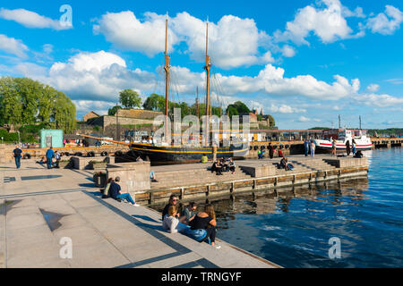 Porto di Oslo Norvegia, vista dei giovani che si rilassano accanto a una banchina nella zona del porto (Aker Brygge) a Oslo in un pomeriggio estivo, Norvegia. Foto Stock