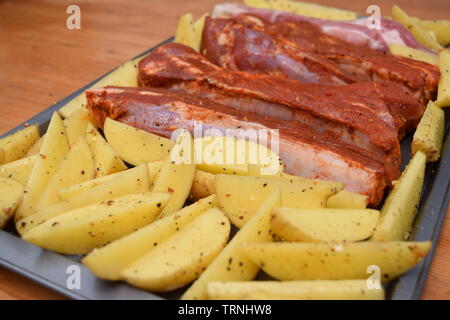 Succosa nervature condita con organici non cotte Spicchi di patate su un piatto d'argento vassoio da forno Foto Stock