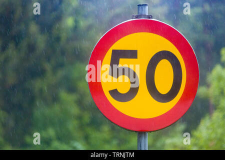 Vista ravvicinata di 50 km chilometri per ora il traffico velocità segno contro bella fuori fuoco sfocato sullo sfondo della natura Foto Stock