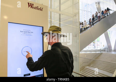 Senior Uomo con schermo a sfioramento del pannello di Directory al Westfield mondo TradeCenter complesso per lo shopping, NYC, STATI UNITI D'AMERICA Foto Stock