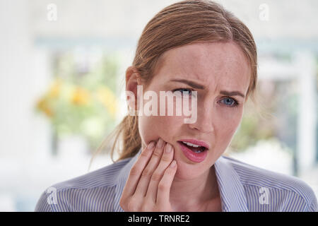 Giovane donna soffre di mal di denti tocchino la ganascia Foto Stock
