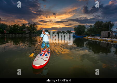 Gura Portitei, Romania - 08 Giugno 2019: l'uomo sul SUP board, stand up paddling al tramonto sul lago nel Delta del Danubio a Gura Portitei, Romania Foto Stock