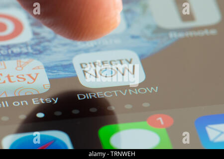MINNEAPOLIS, MINNESOTA / STATI UNITI D'America - 25 Aprile 2019: Persona utilizzando Apple i-phone per premere e accedere alle app DIRECTVNOW / applicazione Foto Stock