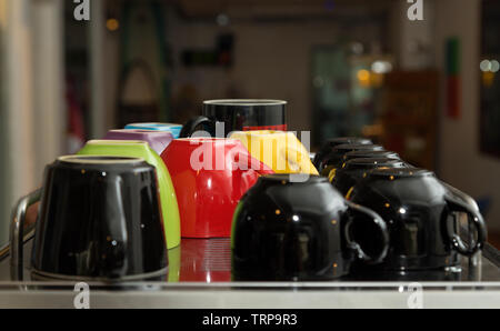 Tazze colorate in una fila in una caffetteria o per la cucina Foto Stock