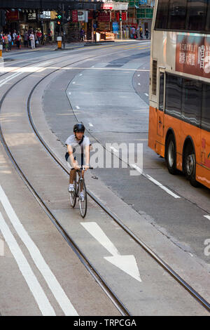 Ciclista in tram lane, la Causeway Bay di Hong Kong SAR, Cina Foto Stock