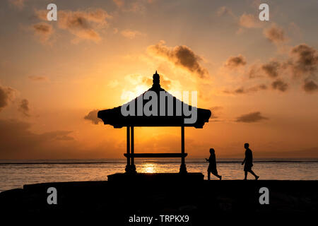 Silhouette giovane a piedi pavilion con sunrise shining a coste Foto Stock