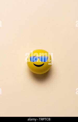 Faccina sorridente sfera con occhiali da sole blu su sfondo pastello Foto Stock