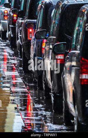 Taxi a Londra sotto la pioggia - una coda di London Black Cabs in attesa per i passeggeri sotto la pioggia battente Foto Stock