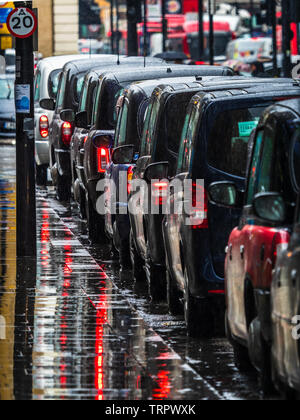 Taxi a Londra sotto la pioggia - una coda di London Black Cabs in attesa per i passeggeri sotto la pioggia battente Foto Stock