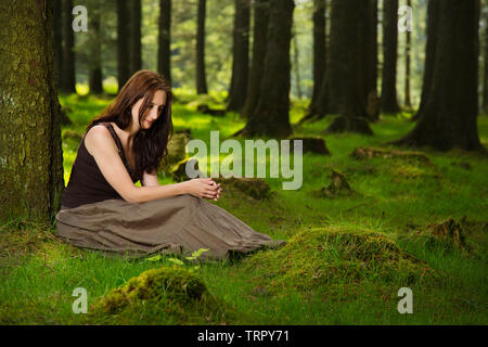 Una ragazza da sola in una foresta Foto Stock