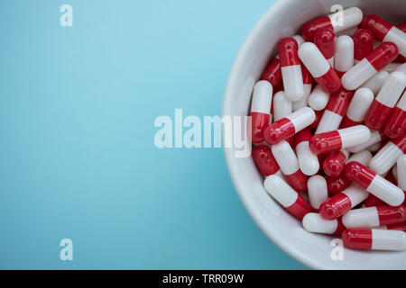 Ciotola di farmaci pillole capsule su blu colore di sfondo Foto Stock