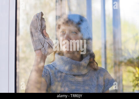 Giovane donna finestra di lavaggio in camera Foto Stock