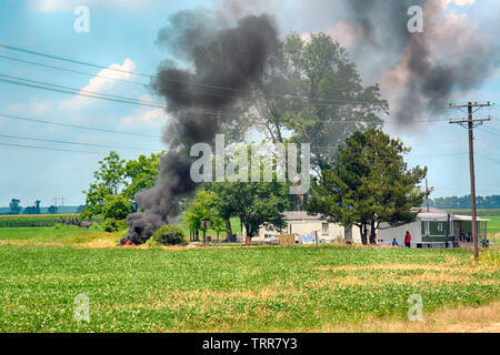 Famiglia rurale esterno con biancheria in asciugatura a fianco di fumo dalla combustione del cestino nel cortile sul loro terreno coltivato nel nord-ovest del Mississippi Foto Stock