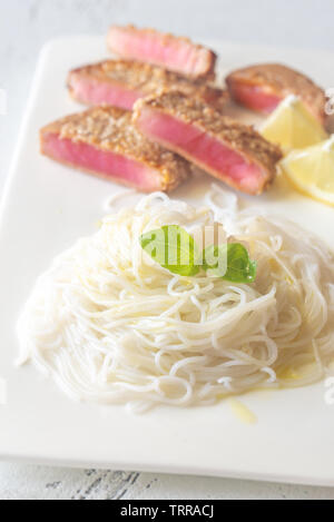 Riso tagliatelle con tonno fritto in semi di sesamo sulla piastra bianca Foto Stock